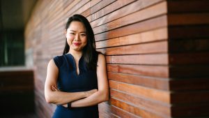 Relaxed looking woman leaning against a wooden wall on a break between stress management training sessions.