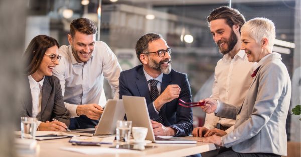 Business team who practices the stress reset 1200x628 Business team who practices the stress reset methodology at a table working and laughing together.